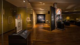 An exhibition space with artifacts displayed on shelves and images on the wall.